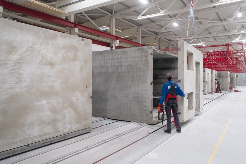 Die Raummodule wurden in der Deutschen Modulhausfabrik aus einem Stück betoniert. Die vorgesetzte Stirnseite enthält Aussparungen für die Verbindung der Steigleitungen auf der Baustelle sowie für den Eingang.